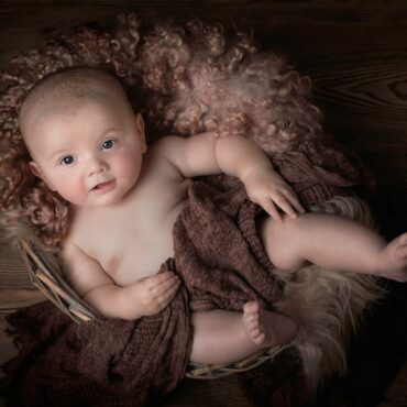 baby lying on brown textile