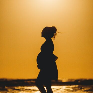 silhouette of woman standing on beach during sunset